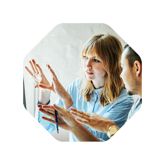 A woman and a man in discussion, gesturing towards an idea or concept, possibly related to design planning.