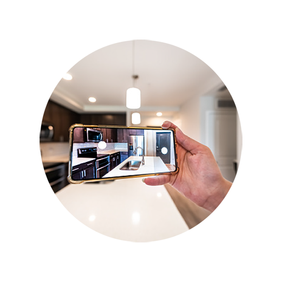 A person holding a smartphone in a modern kitchen, using an AR-based tool to visualize a new kitchen design on the screen.