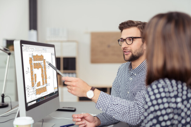 A man and woman are focused on a computer screen