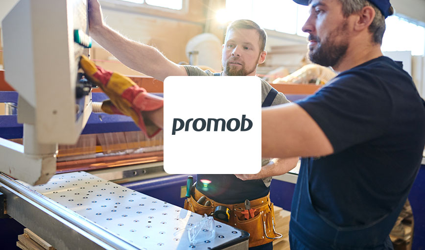 Two men working on a machine with Promob logo.