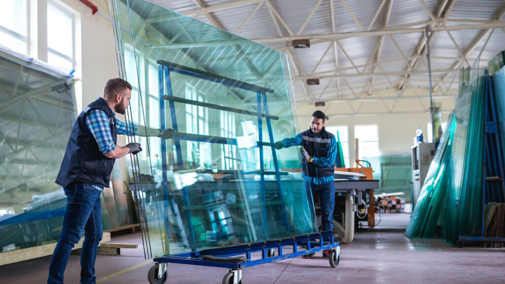 Two men collaborate on glass production in a factory