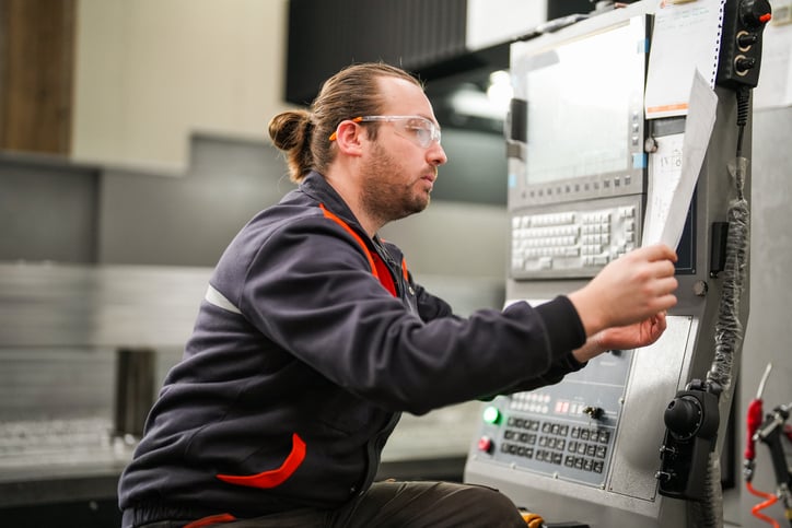 A factory technician implementing processes at a door manufacturing plant, operating a control panel with precision to ensure smooth operation.