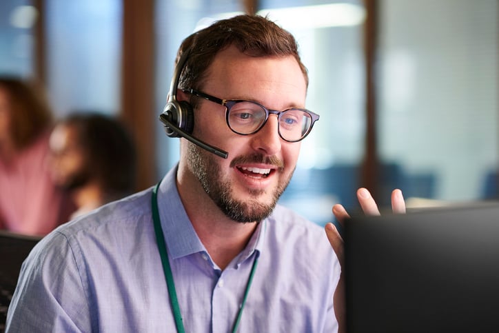 An IT support professional wearing a headset, engaged in a virtual call, offering customer service or technical assistance.