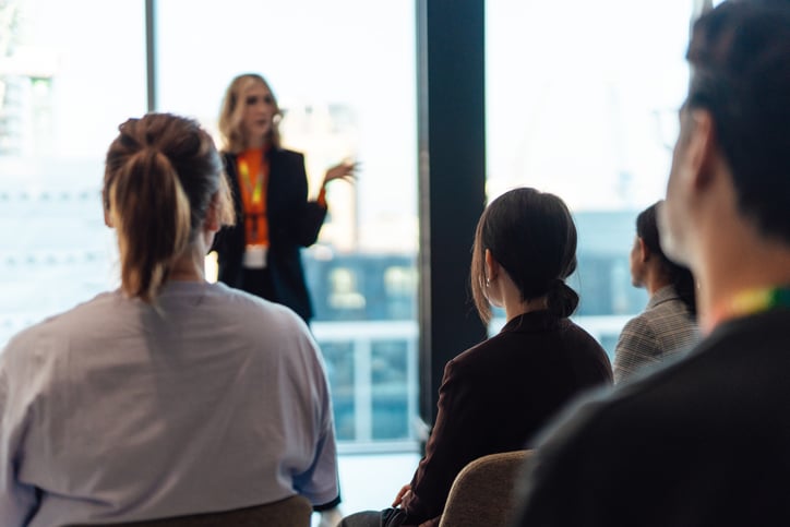 A professional conducting a training session in front of an audience, discussing key points in a business setting