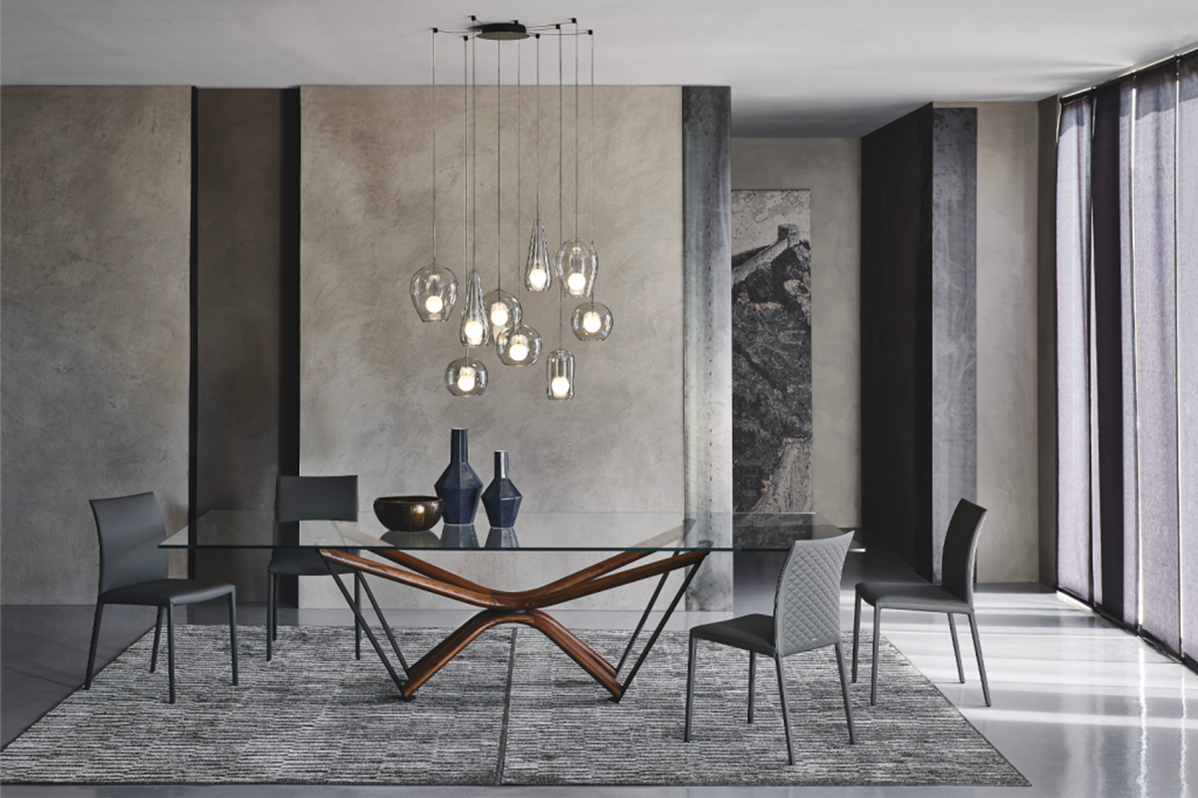 A stylish dining room setup with a glass table, wooden legs, and modern chairs.