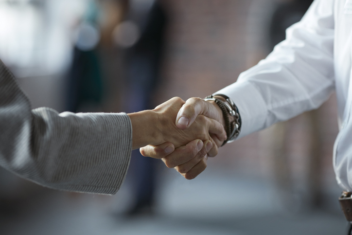 Close-up of businessman & businesswoman making handshake at convention