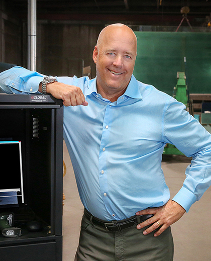 A GlasPro representative standing confidently in the production facility next to a workstation showcasing FeneVision software.