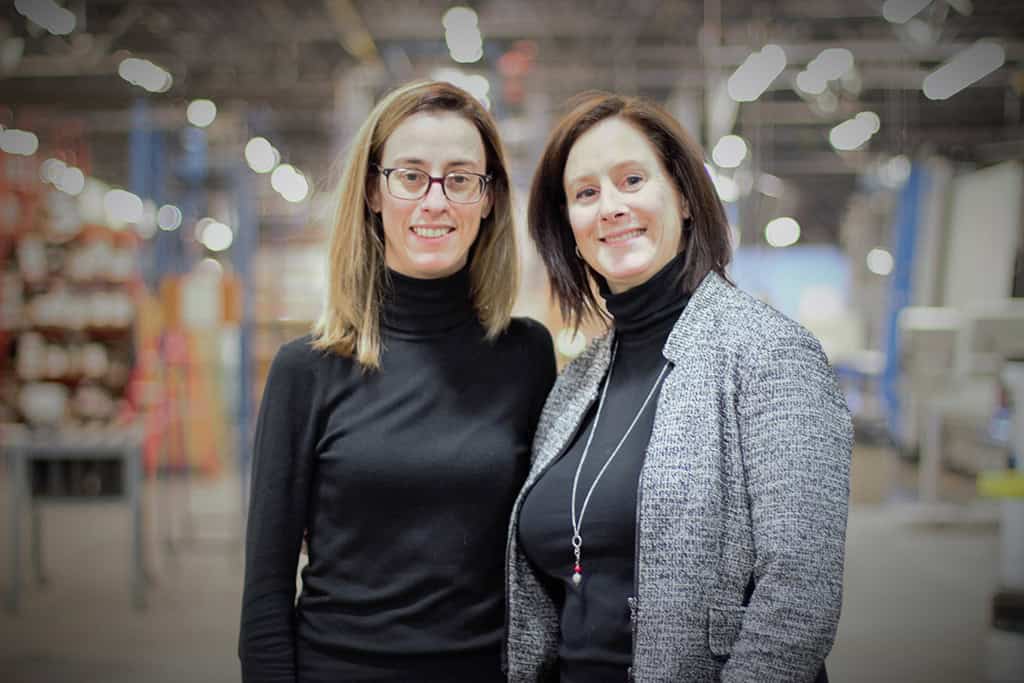 Two women standing in an industrial warehouse