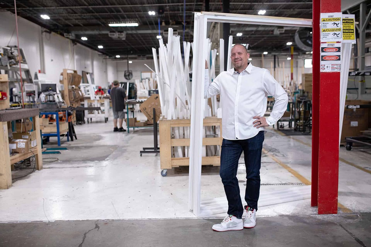 A man is standing in a factory, next to a white door frame