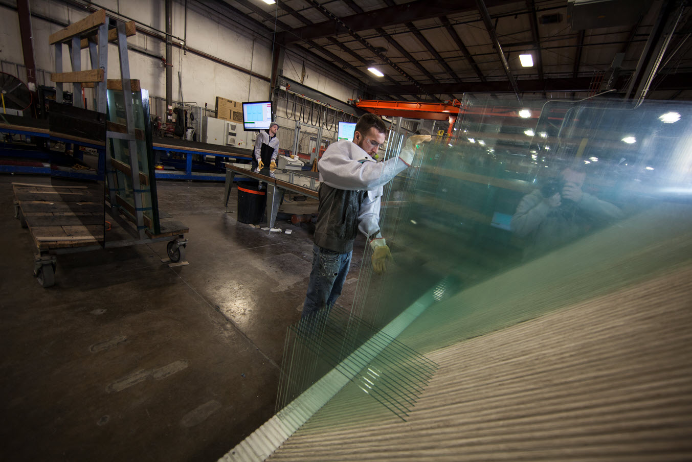 A TriStar Glass technician carefully inspecting large glass panes in the factory, representing pre-FeneVision production challenges.