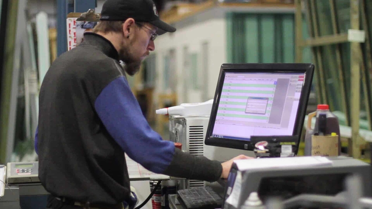 A man focused on his computer while working in a factory setting