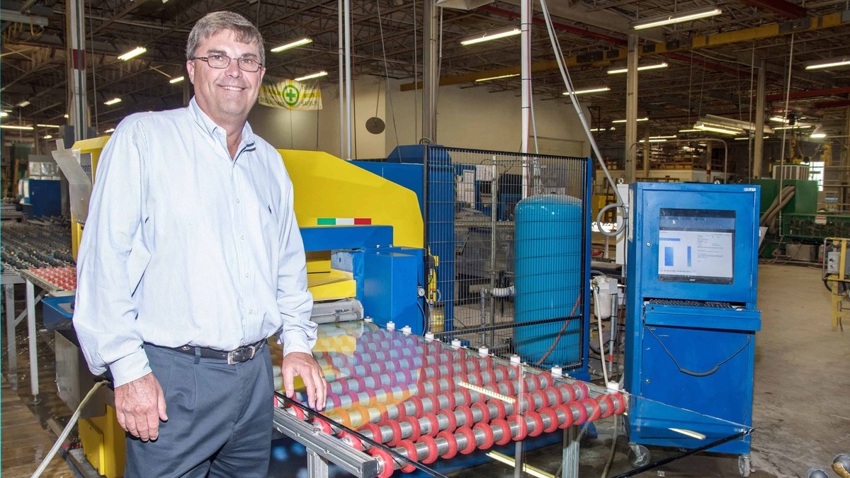 A man stands in front of a factory machine