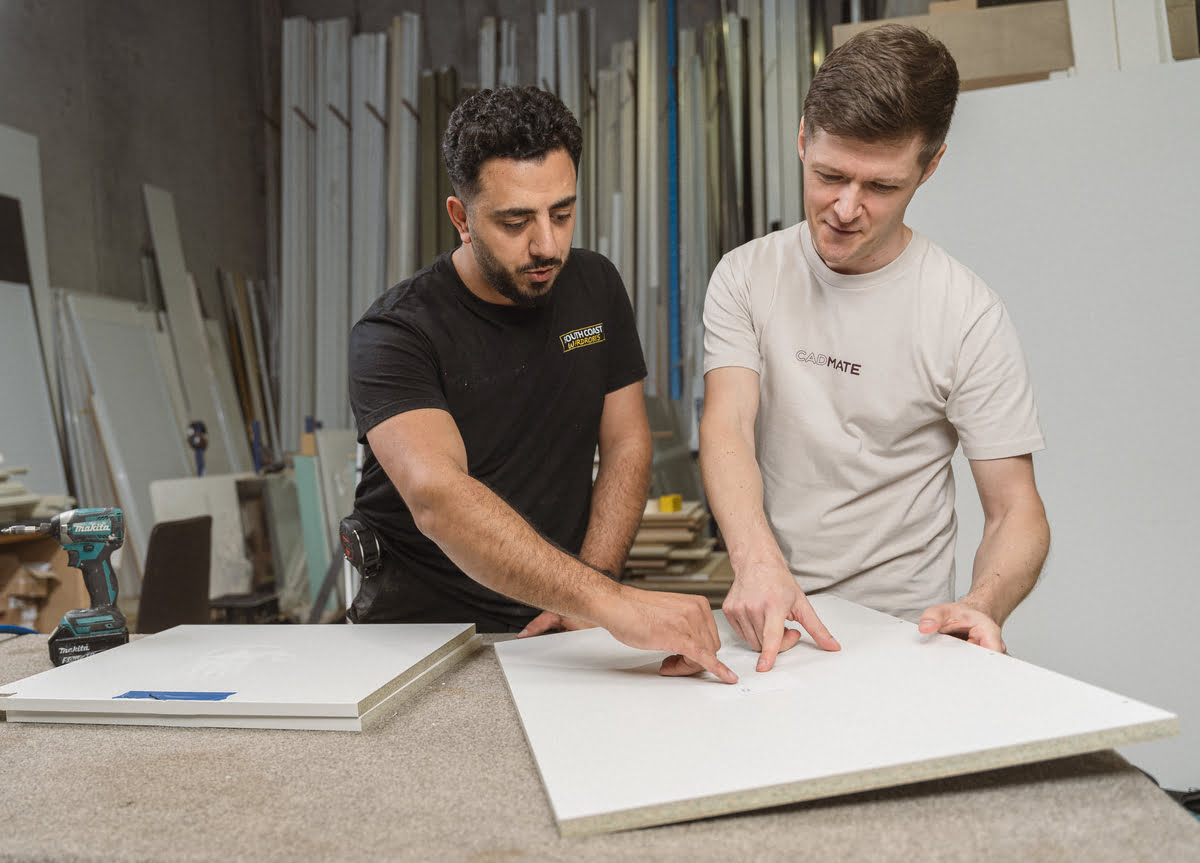 Two men collaborate on a piece of paper in a workshop